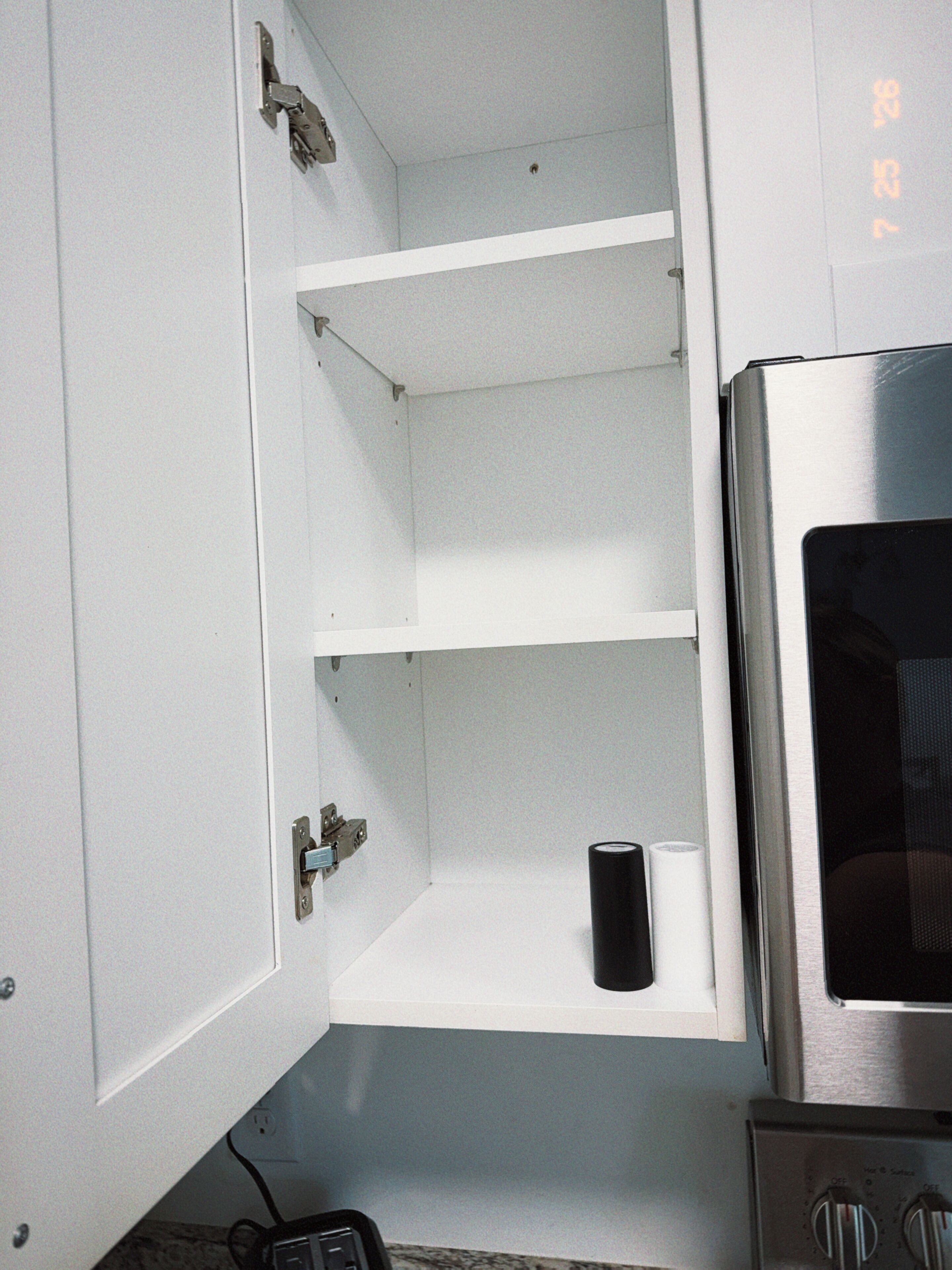 A kitchen with white cabinets, a stainless steel oven, and a countertop with a power strip.