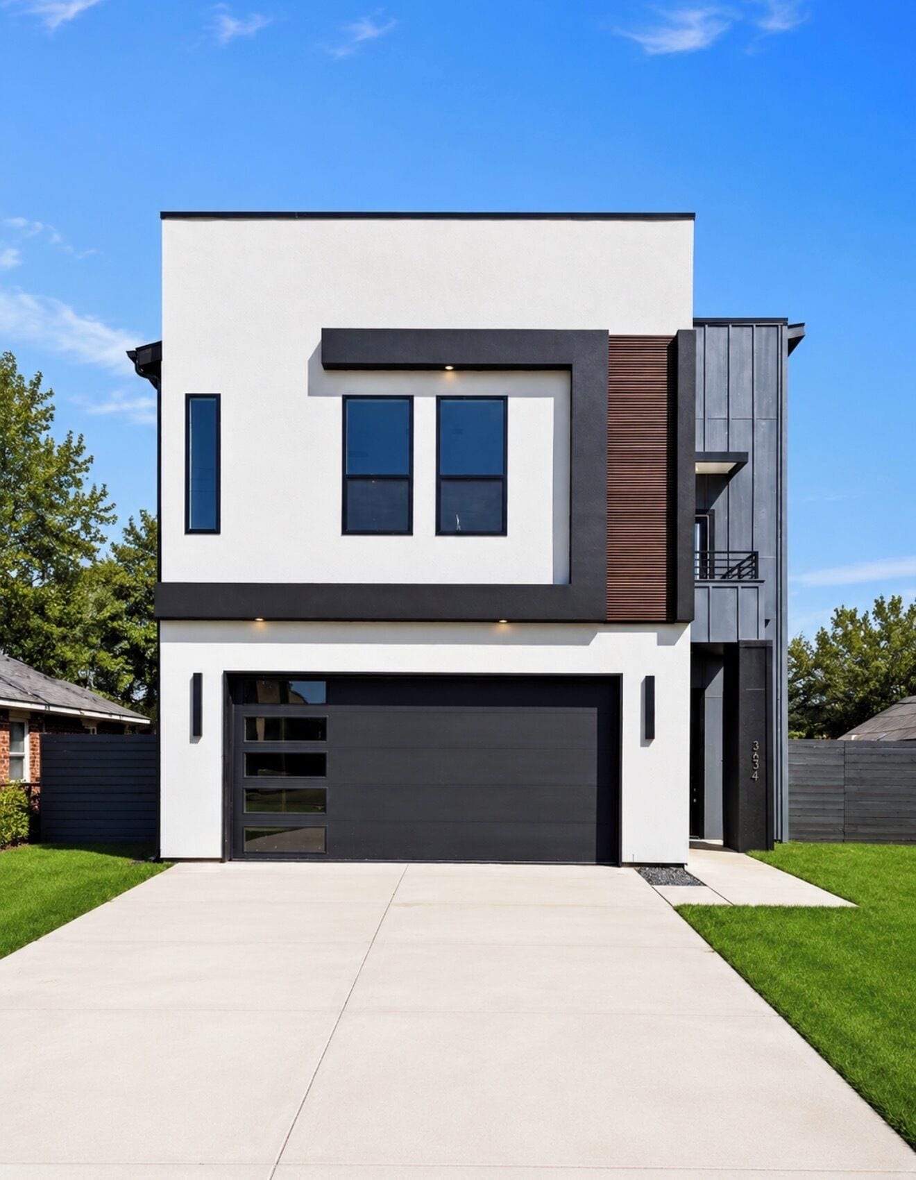 A modern two-story house with a garage, a balcony, and a large driveway.