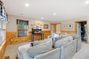 A cozy living room with a sofa set, a television on a wooden stand, and a window with blinds. - Wild Turkey | Sleeps 18! Views, Hot Tub, & MORE! (Sevierville)
