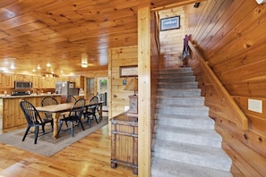 A wooden interior with a kitchen, dining area, and a staircase. - Wild Turkey | Sleeps 18! Views, Hot Tub, & MORE! (Sevierville)
