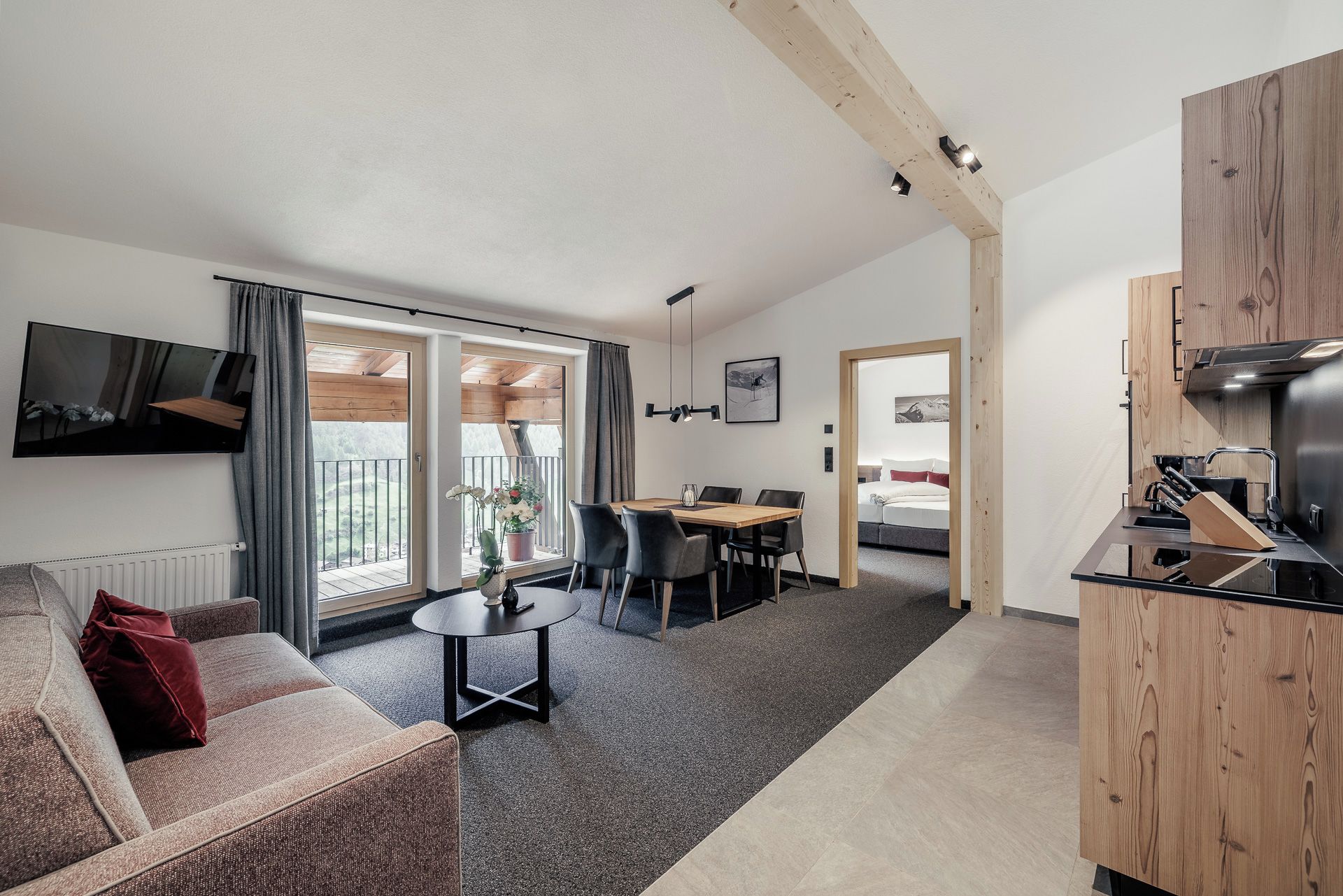 Ein modernes Wohnzimmer mit einer Couch, einem Esstisch und einer Küchenzeile mit Herd.