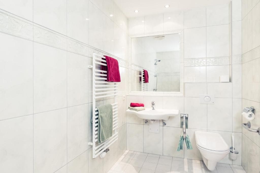 Un baño moderno con lavamanos, espejo y retrete blancos.