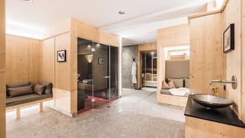 A modern bathroom with a glass shower enclosure, a wooden bench, and a sink with a bowl basin.