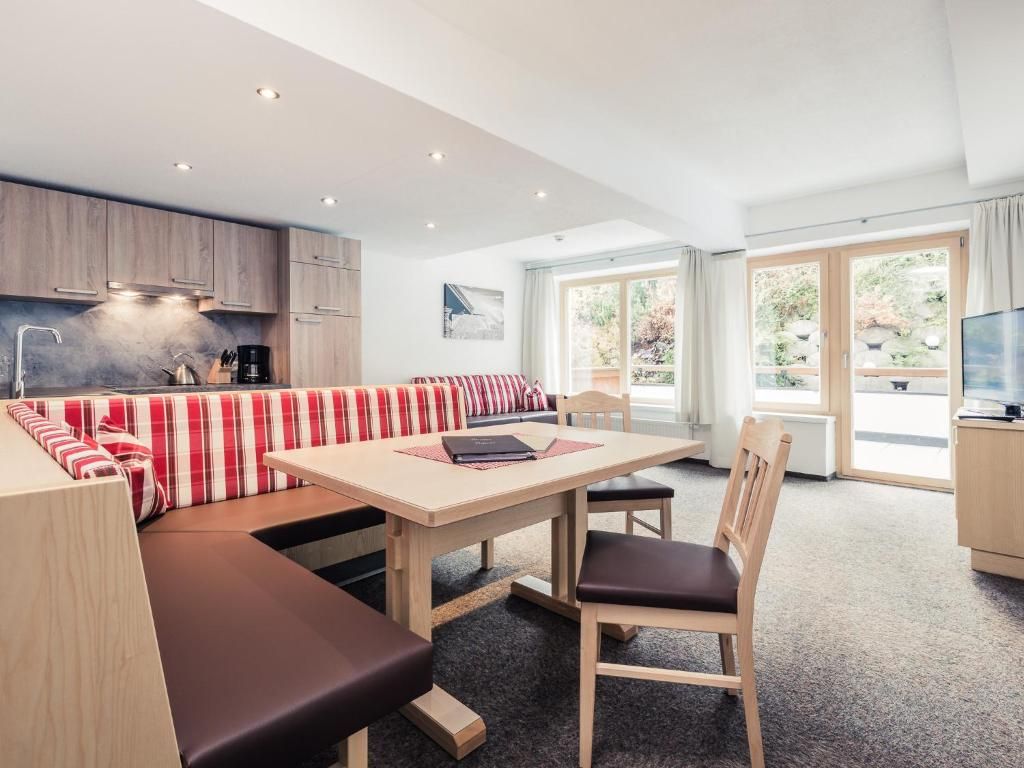 Una cocina moderna con armarios de madera, un comedor con mesa y bancos, y un amplio ventanal que ofrece vistas al exterior.
