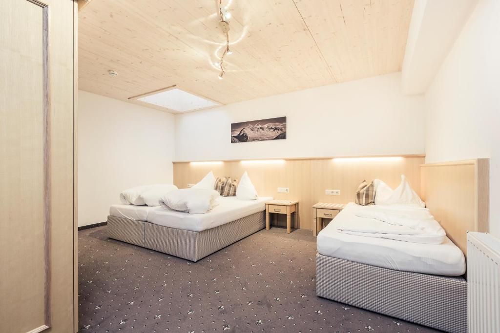 A hotel room with two beds, a small table, a chair, and a picture on the wall.