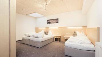 A hotel room with two beds, a small table, a chair, and a picture on the wall.