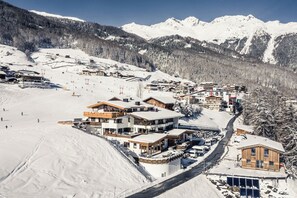 Een met sneeuw bedekt bergdorp met skipistes, houten gebouwen en een heldere lucht.