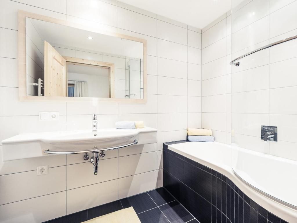 Un bagno con lavandino bianco, uno specchio, una vasca e una doccia.