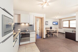 A compact kitchen with modern appliances, a dining area with a table and chairs, and a television.