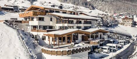Een hotel met meerdere verdiepingen, met een skipiste op de achtergrond.