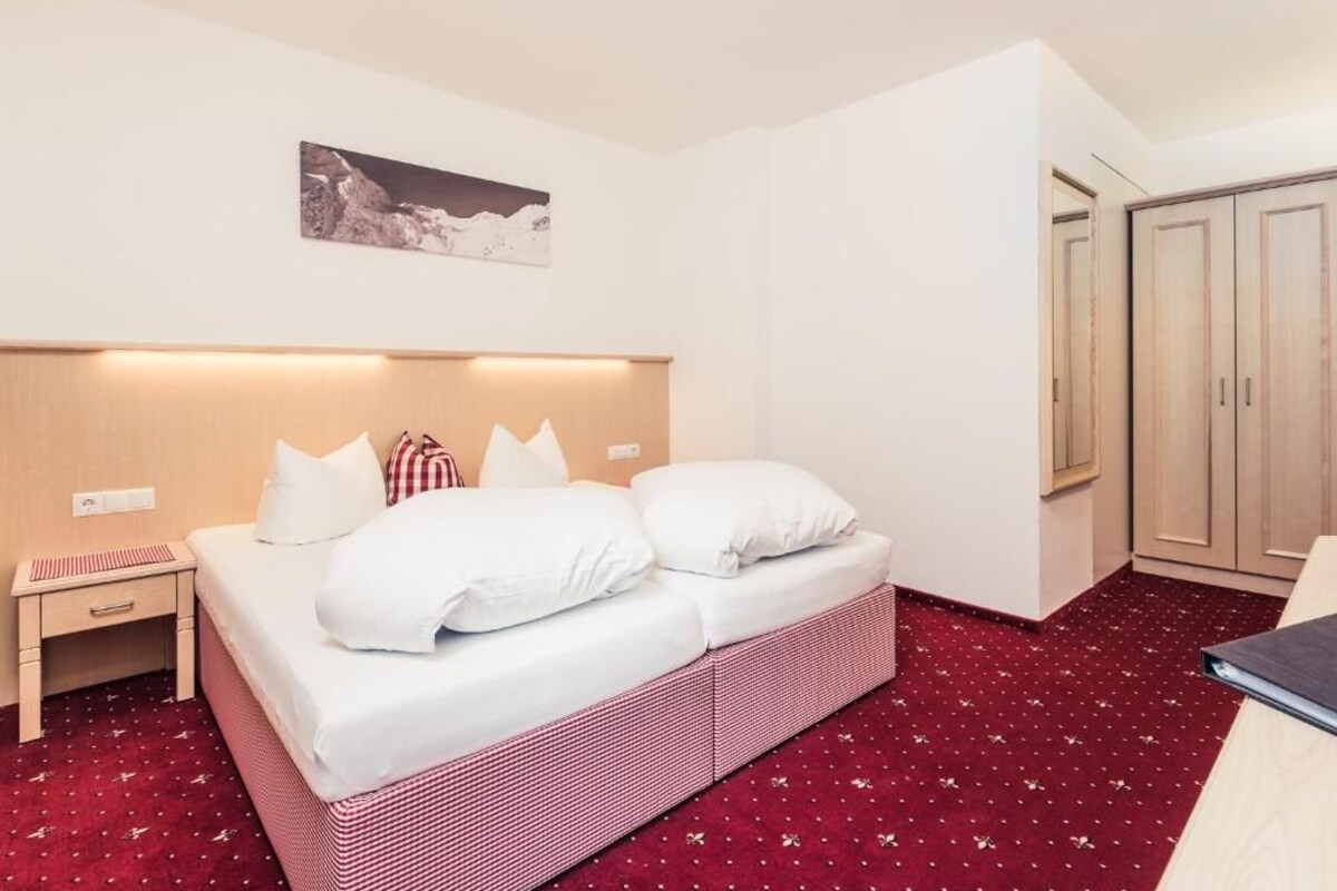 Een hotelkamer met een bed, een nachtkastje, een kast en een aan de muur bevestigd schilderij.