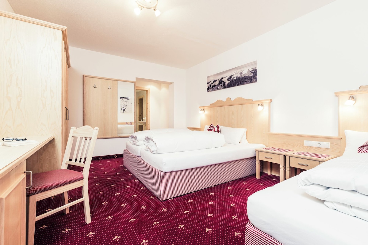 Een hotelkamer met een bed, een bureau, een stoel, een kledingkast en een spiegel.