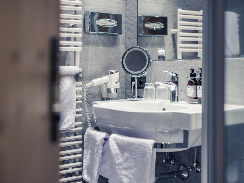 A bathroom with a round mirror, white sink, and towel rack.