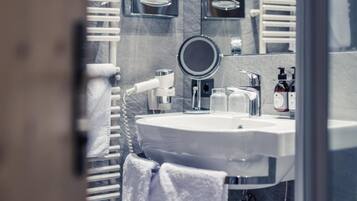 A bathroom with a round mirror, white sink, and towel rack.