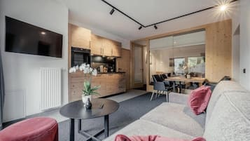 A modern living room with a sofa, a coffee table, and a TV mounted on the wall.