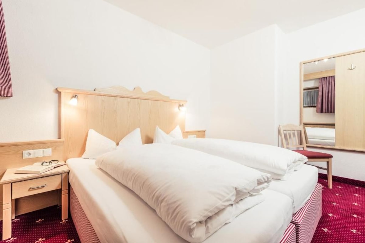 Een hotelkamer met een bed, nachtkastje en spiegel.