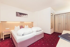 Una habitación de hotel con una cama, mesita de noche y armario.