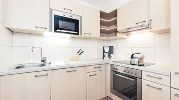 A modern kitchen with a built-in microwave, a coffee maker, and a kettle on the countertop.
