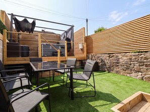A patio area with a glass-top table, metal chairs, and a wooden fence. - 2 Makant Street (Bolton)