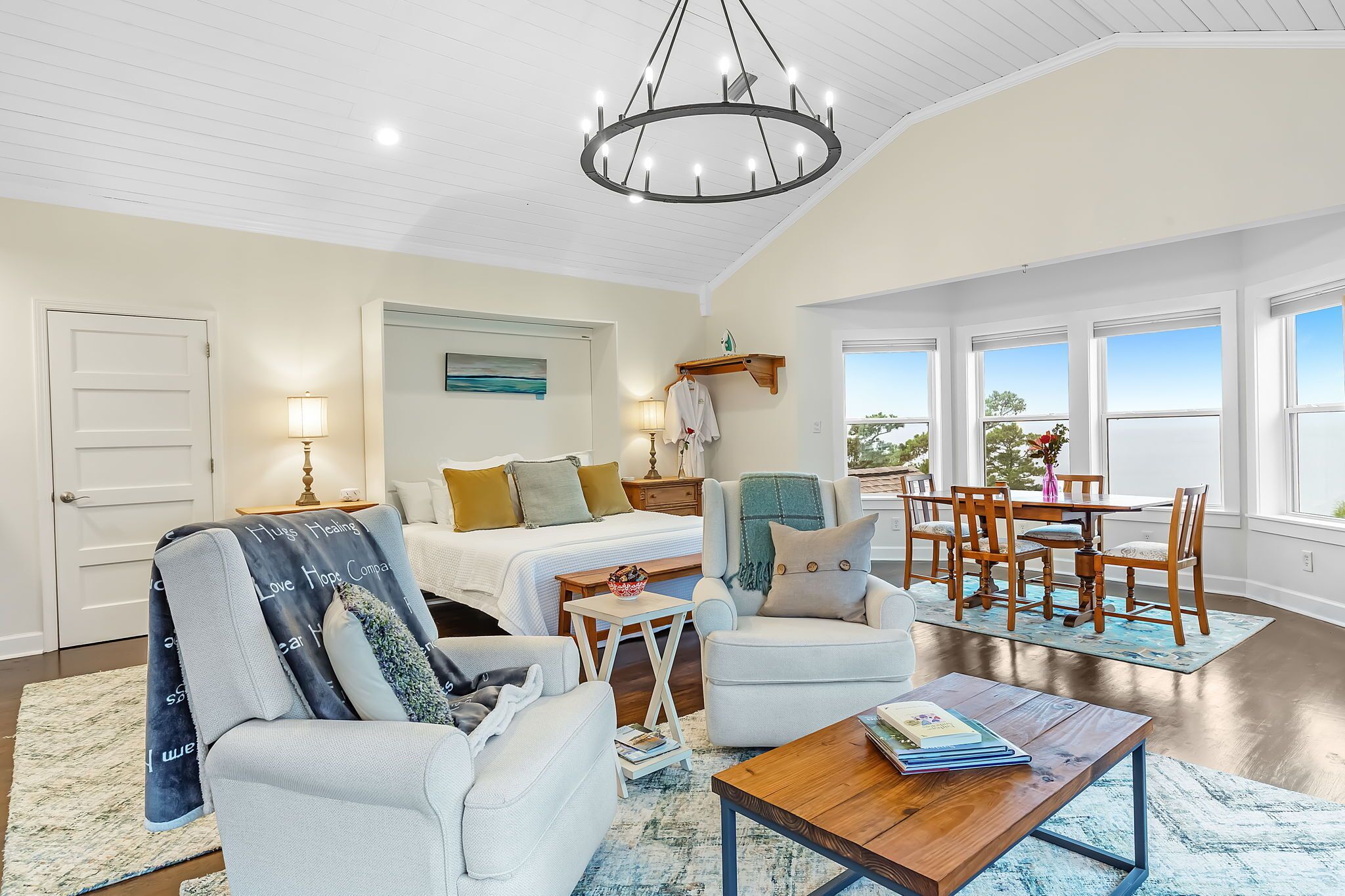 A spacious living room with a large bed, a dining area, and a view of the outdoors.