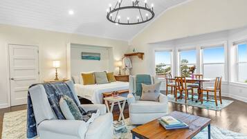 A spacious living room with a large bed, a dining area, and a view of the outdoors.