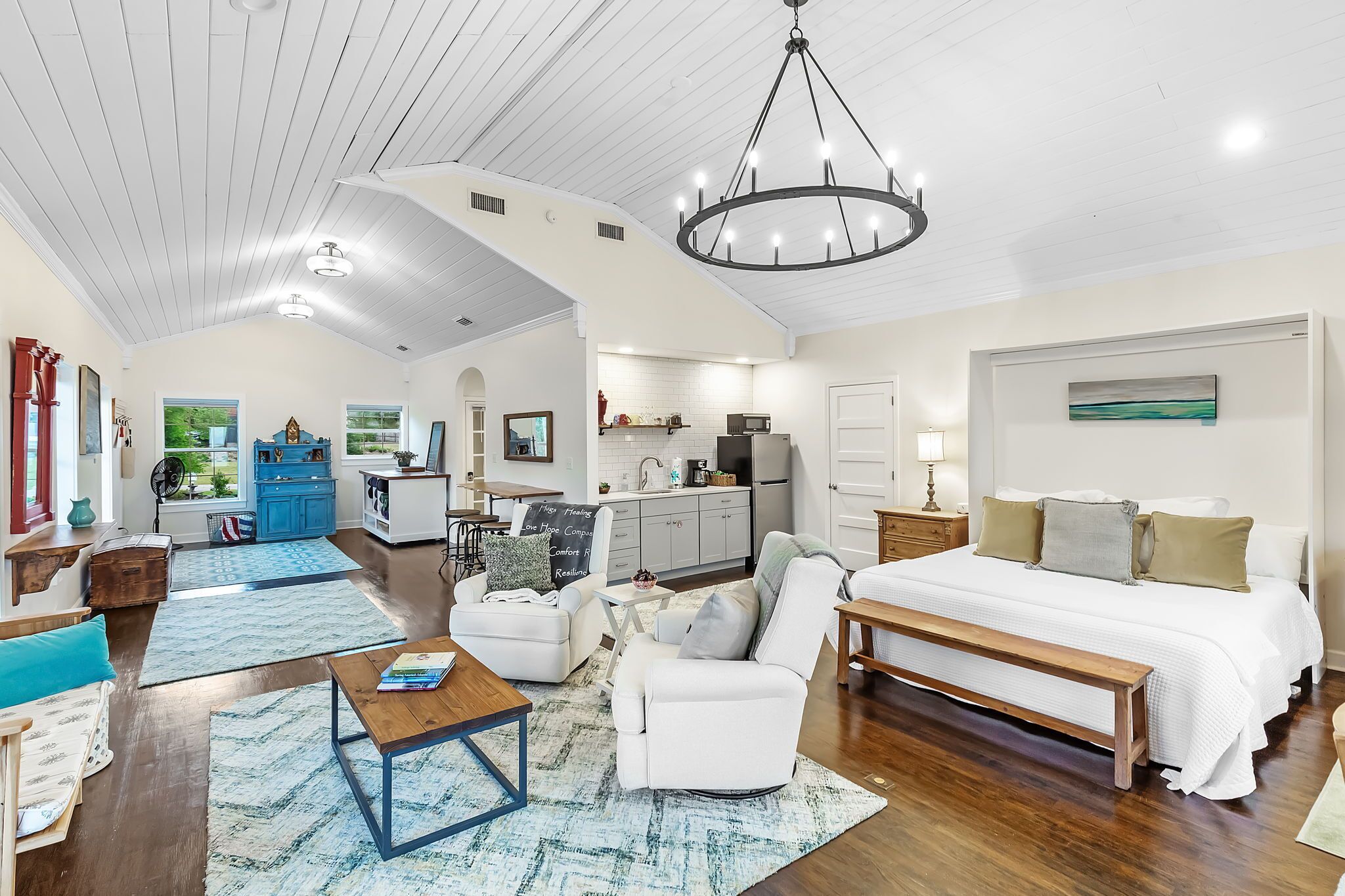 A spacious living area with a large bed, a dining table, and a kitchen in the background.