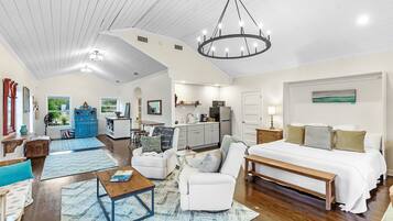 A spacious living area with a large bed, a dining table, and a kitchen in the background.