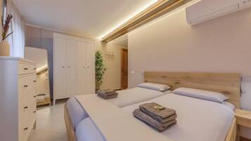 Ein modernes Schlafzimmer mit zwei Betten, einem Kleiderschrank und einem Nachttisch.
