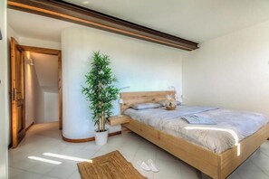 A bedroom with a wooden bed, a potted plant, a nightstand, and a doorway leading to another room. - Agriturismo Borgata Levita "Molinara" App (Veneto)