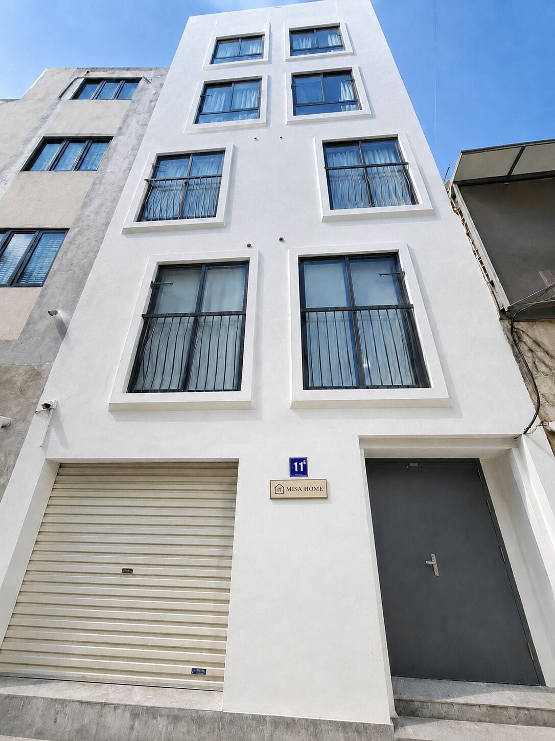 Un immeuble à plusieurs étages, doté d’une façade plate, de plusieurs fenêtres et d’une porte de garage.