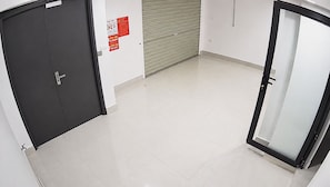 A hallway with a closed door, a fire safety notice, and a closed shutter door.