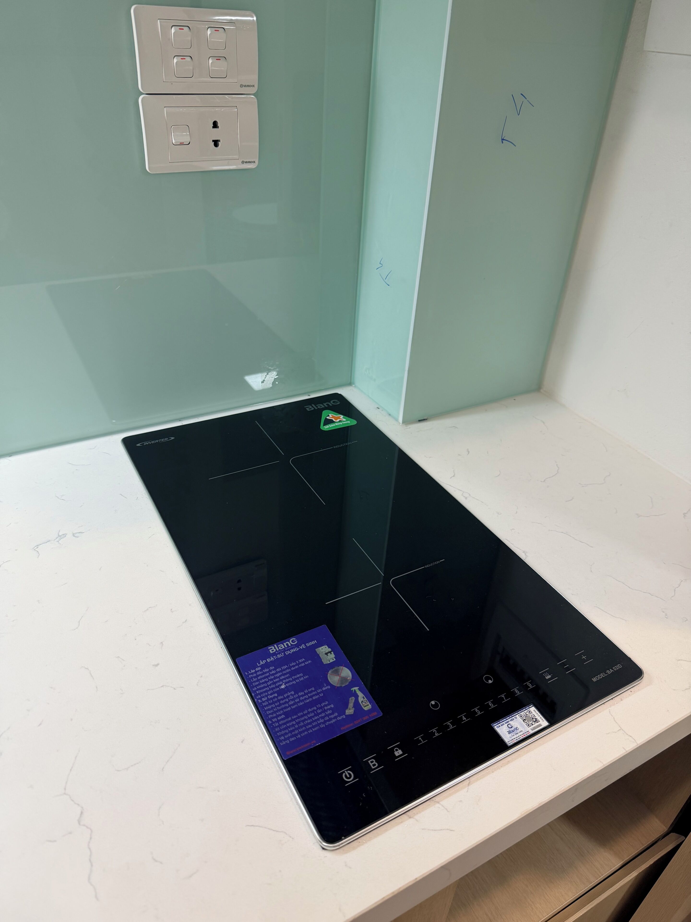Une cuisine moderne dotée d’une plaque de cuisson à induction intégrée et d’un dosseret en acier inoxydable.