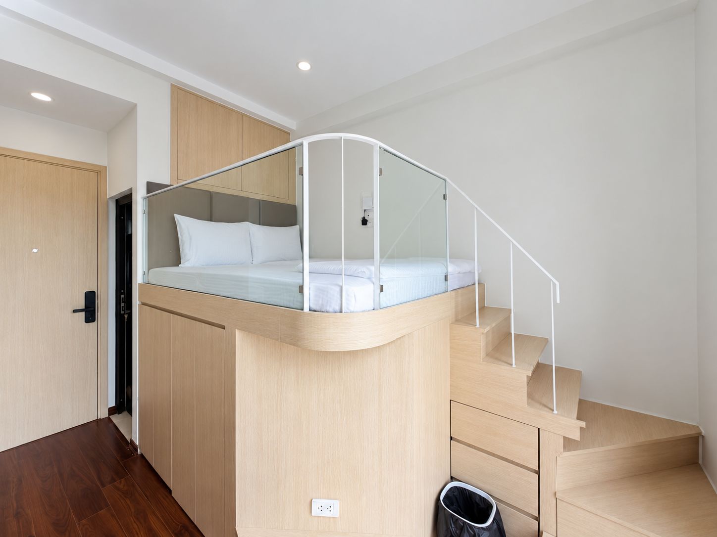 Ein modernes Schlafzimmer mit integriertem Bett, einer gläsernen Wendeltreppe und Holzboden.