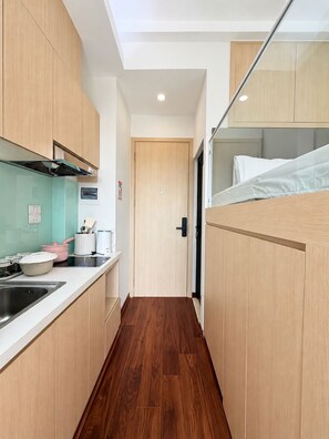 A narrow kitchen with wooden cabinets, a built-in stove, and a sink. - Misa Home (Hanoi)