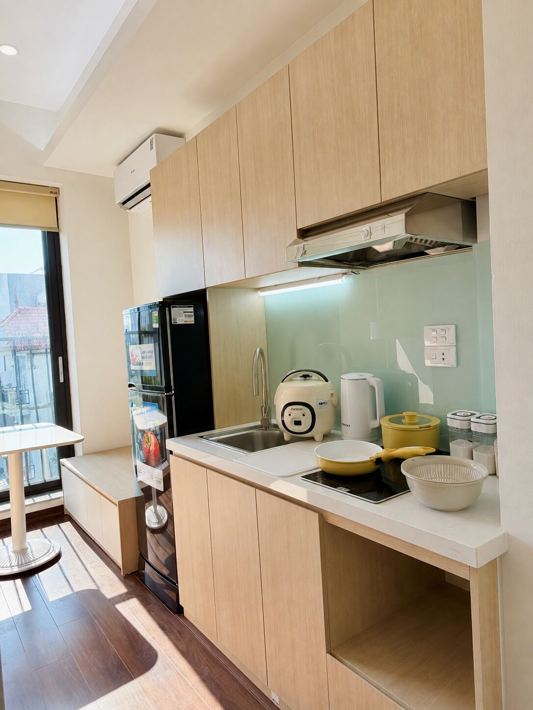 Une cuisine moderne avec des meubles en bois, un réfrigérateur noir, une machine à café et un évier.