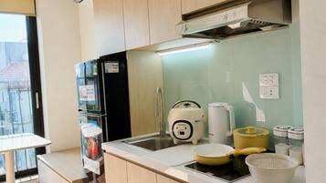 Una cocina moderna con armarios de madera, un refrigerador negro, una cafetera y un lavamanos.