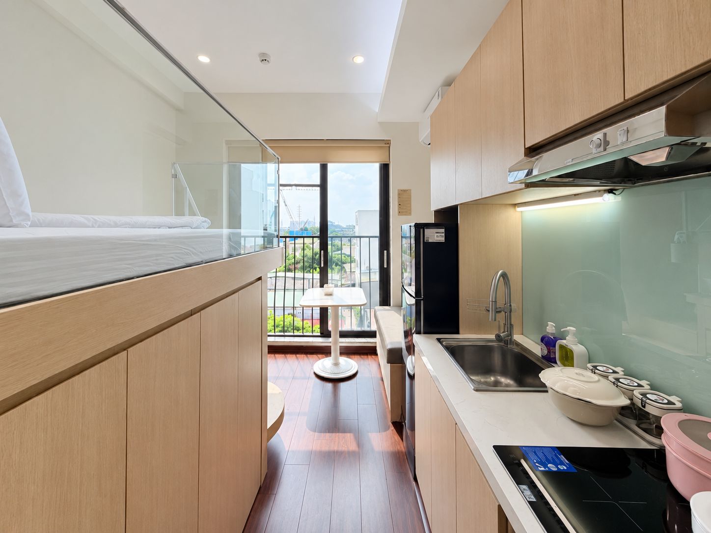 A compact kitchen with a modern design, a dining area with a small table, and a balcony with a view.