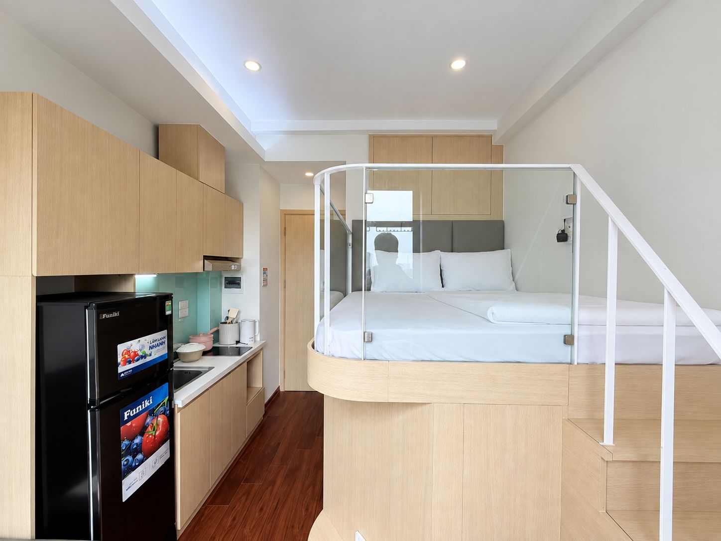 Une chambre d’hôtel de taille réduite, comprenant un lit, une kitchenette et une petite salle de bain.