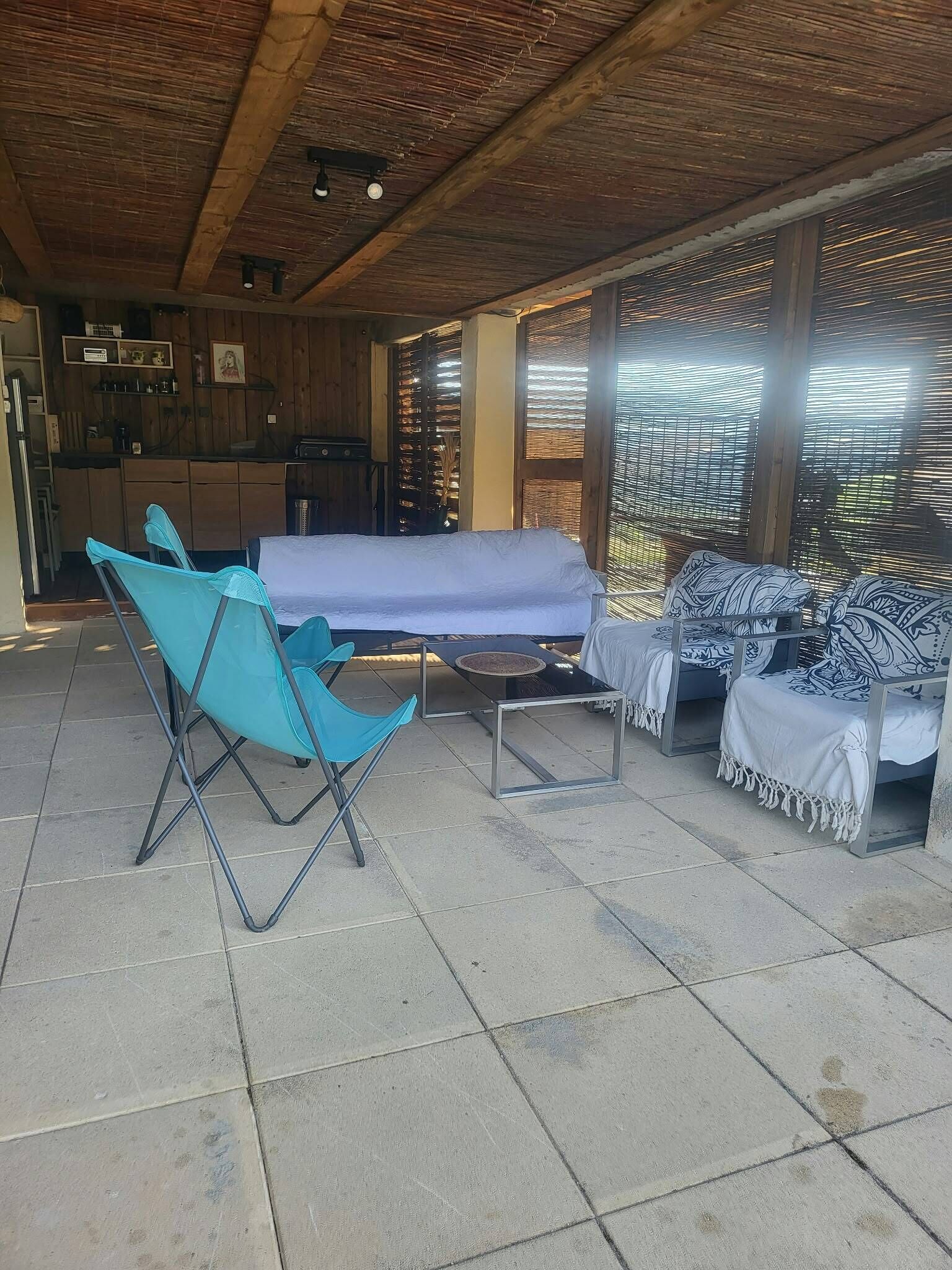 Un espace extérieur abrité, aménagé avec une table, des chaises et un canapé.
