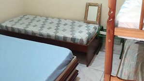 A bedroom with a single bed, a wooden headboard, a bedside table, and a green chair. - Pousada Maanaim (Rio de Janeiro)