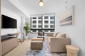 A modern living room with a flat-screen TV, a sofa, a coffee table, and a large window with a city view. - Downtown Miami Luxury 1 Bed with Free Parking and Gym Pool Basketball Court (Miami)