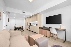 Un salon moderne comprenant un canapé, une table à manger et un coin cuisine avec des meubles en bois et un téléviseur à écran plat.