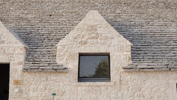 Un edificio de piedra con un frontón triangular y una ventana pequeña.
