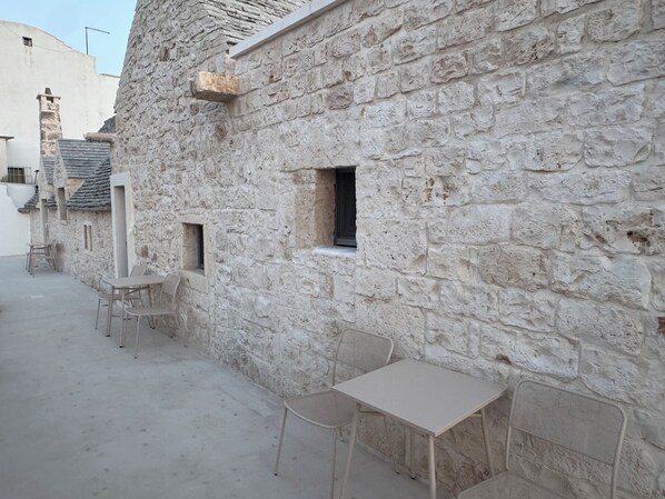 A stone building with a small window and a table with chairs.
