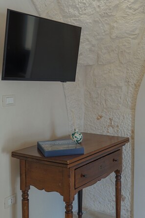 A wooden desk with a television mounted on the wall above it.