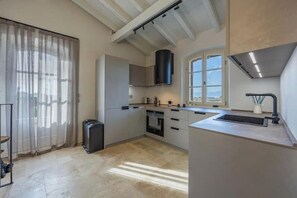 Eine moderne Küche mit Backofen, Spüle aus Edelstahl und einem Fenster, das für natürliches Licht sorgt.