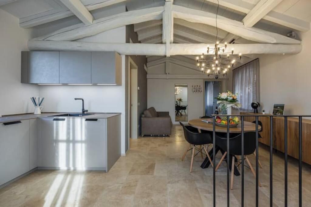A modern kitchen with a central island, a dining area with a wooden table and chairs, and a living space with a sofa and a coffee table.