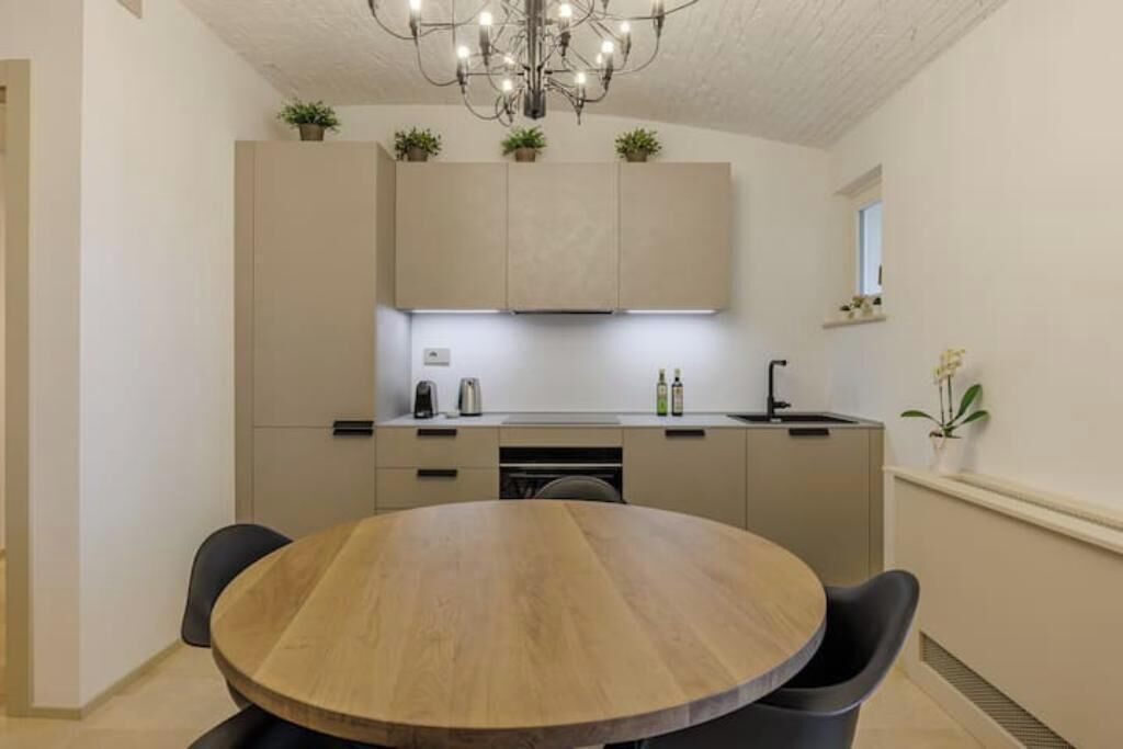 Eine moderne Küche mit einem runden Holztisch und schwarzen Stühlen, ausgestattet mit einem Einbauofen und einer Spüle.
