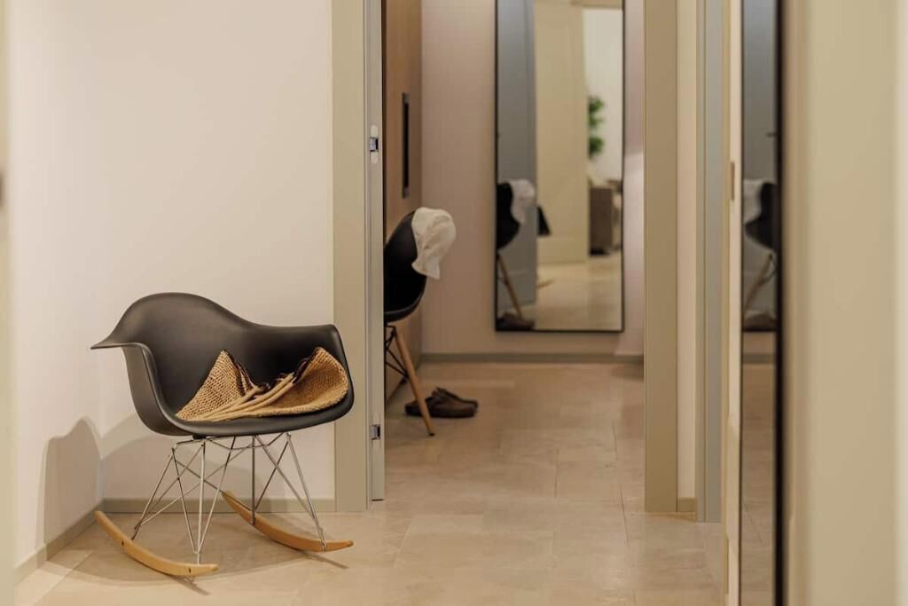 Ein modernes Interieur mit einem einzigartigen Schaukelstuhl und einem Flur, der zu einem Raum mit Spiegeln führt.