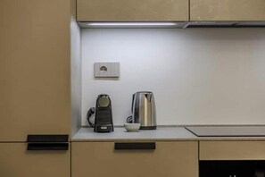 Et tekøkken med kaffemaskine, elkedel og en stikkontakt på væggen.